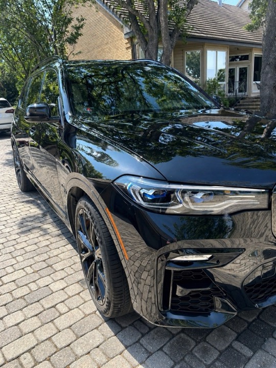 Black BMW X7 with swirl-free corrected paint on a paver driveway, Austin
